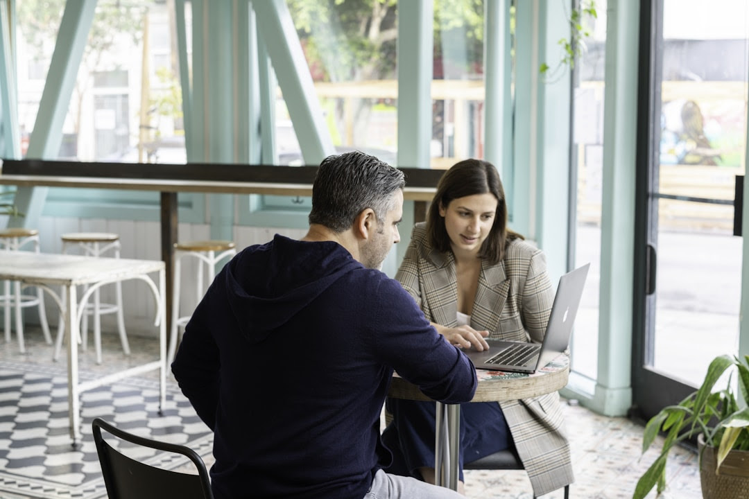 A man and woman collaborate at a table with a laptop, discussing the sales velocity system and its effects on sales operations
